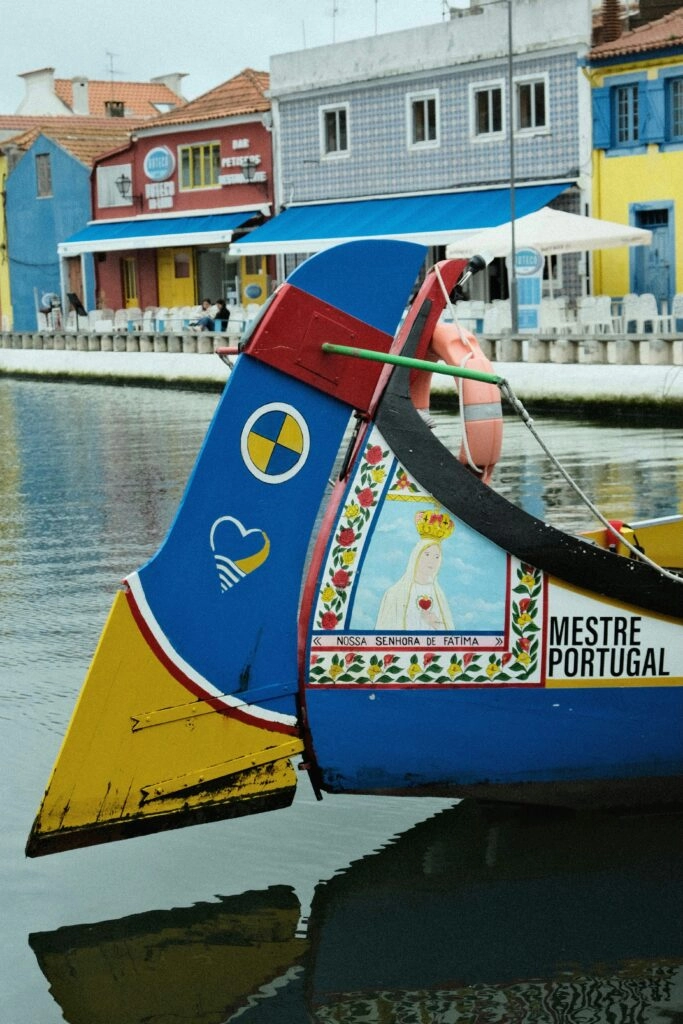 Kleurrijke moliceiro-boot op de grachten van Aveiro, het ‘Venetië van Portugal’, met traditionele huizen op de achtergrond.