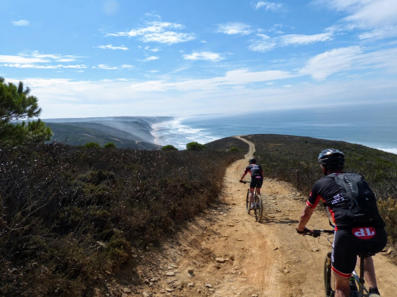 Mountainbikers op de kustroute van de Costa Vicentina, Portugal – fietsen langs kliffen en oceaan tijdens MTB-vakantie Algarve.