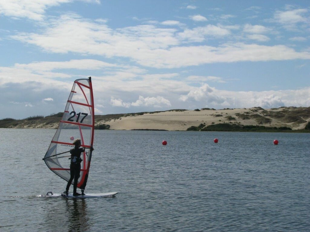 Windsurfer voor de duinen op de Curonische Spit in Litouwen, met uitzicht op het duinlandschap.