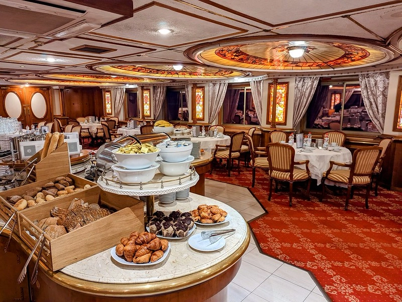 Ontbijtbuffet in het panoramarestaurant van de MS Prinzessin Katharina met vers brood, gebak en gedekte tafels in klassieke setting.