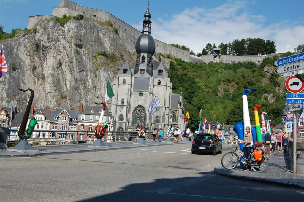 Fietser op de brug van Dinant met uitzicht op de Collegiale Kerk en de citadel, een iconisch hoogtepunt langs de Belgische Maasroute tijdens de 5-Landen Fietsvakantie.