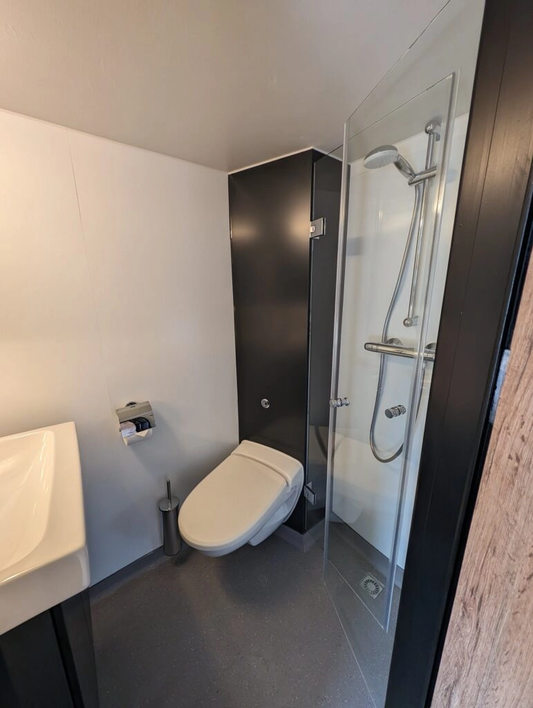 Badkamer van het hoofddek standaardhut op MS Princess met moderne douchecabine, toilet en compacte wastafel; eigentijdse afwerking in licht en donker design.