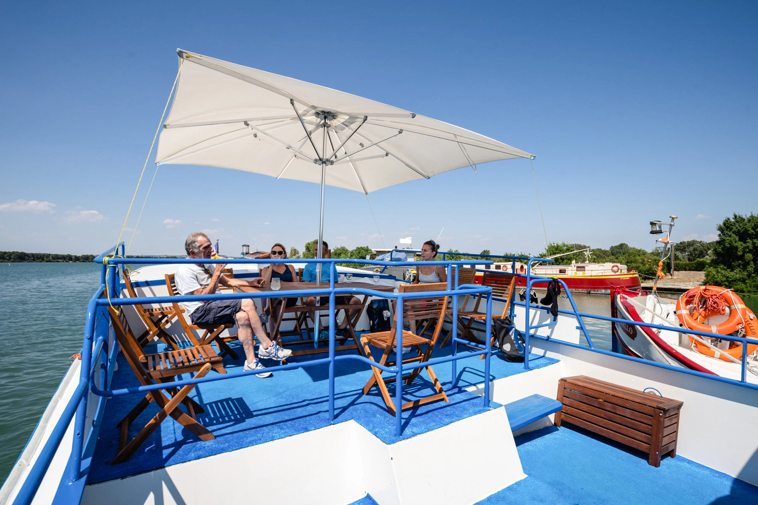 Guests relaxing on the sun deck of the barge Caprice under a parasol during a bike & barge holiday in Provence and the Camargue