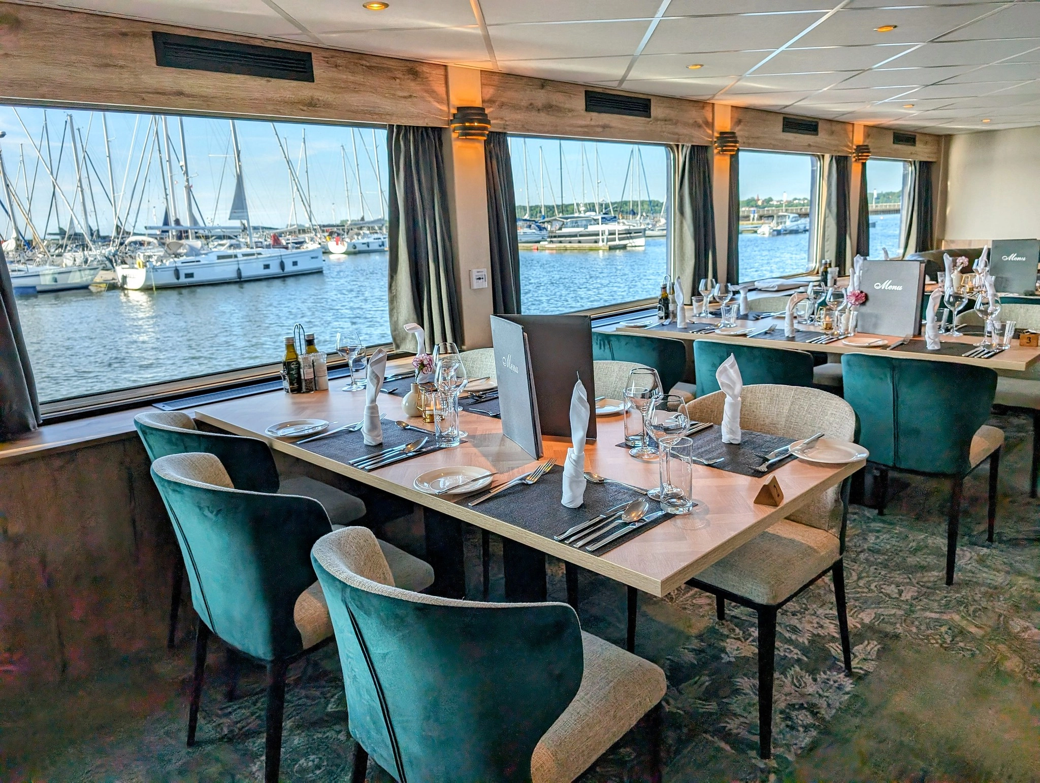 MS Princess restaurant with large windows overlooking a marina and elegantly set tables for breakfast or dinner.