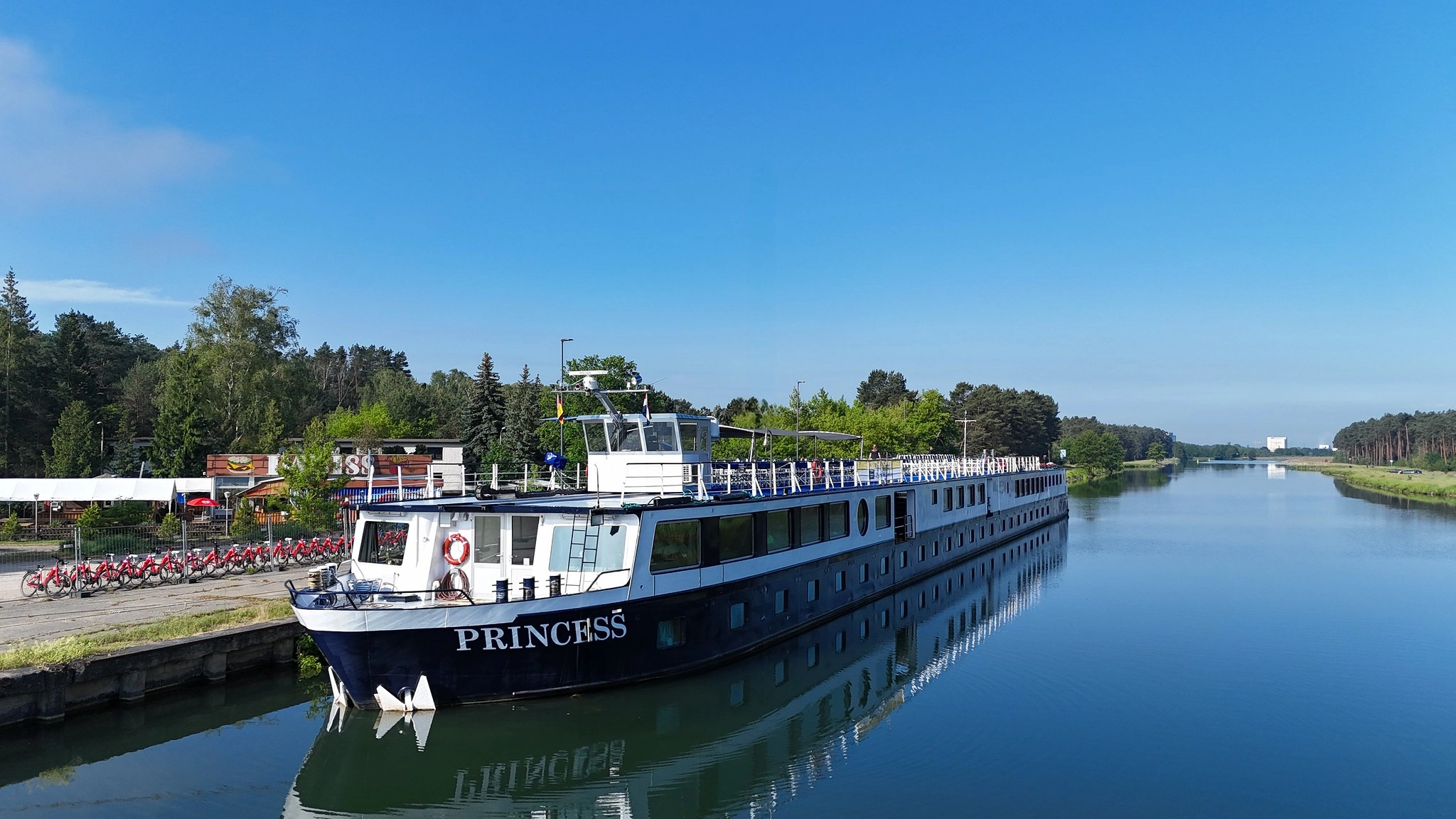 The MS Princess moored on the Oder–Havel Canal, with clear blue water and views of the surrounding landscape.