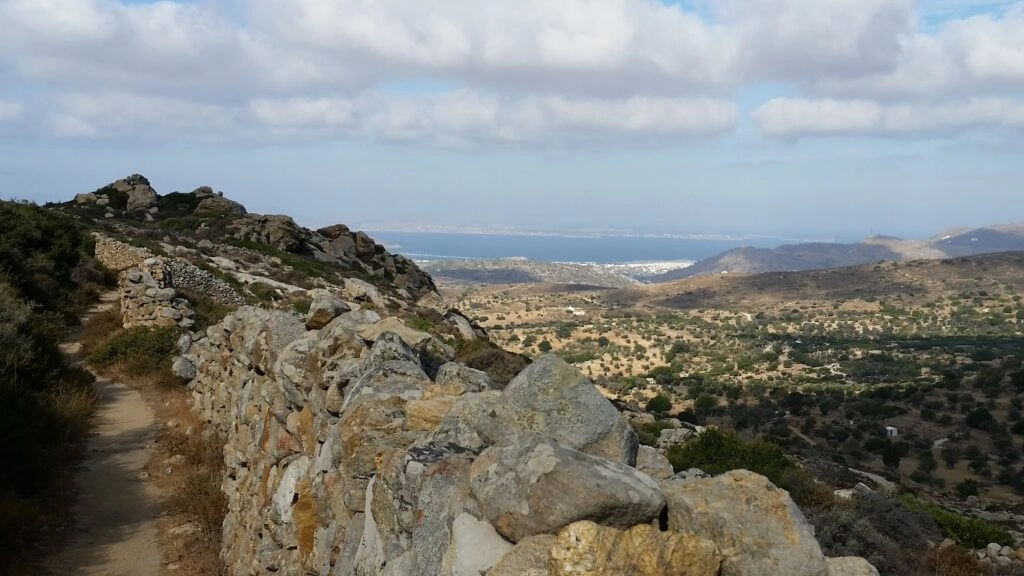 Wandelpad met stenen muurtjes in de Tragea-vallei bij Chalki op Naxos, met uitzicht over het groene binnenland en de zee.