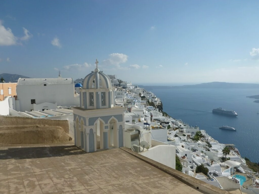 Witte kerk en uitzicht over de caldera van Fira op Santorini tijdens een wandelvakantie in Griekenland.