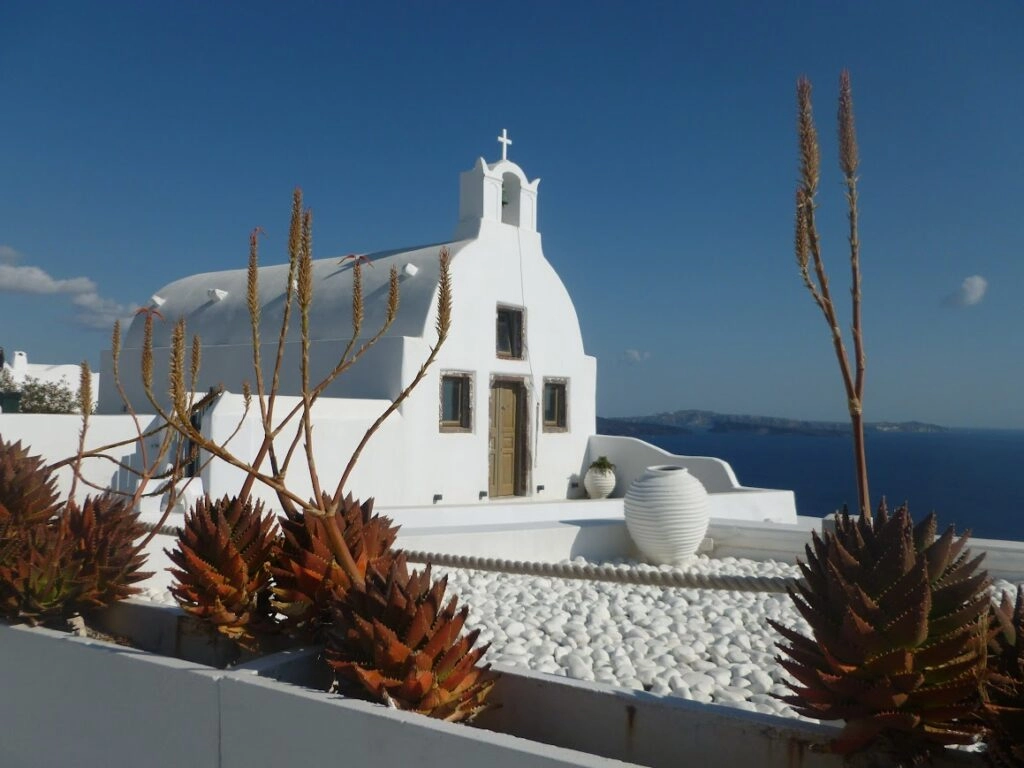 Witte kapel op Santorini met uitzicht over de caldera en de diepblauwe zee van de Cycladen.