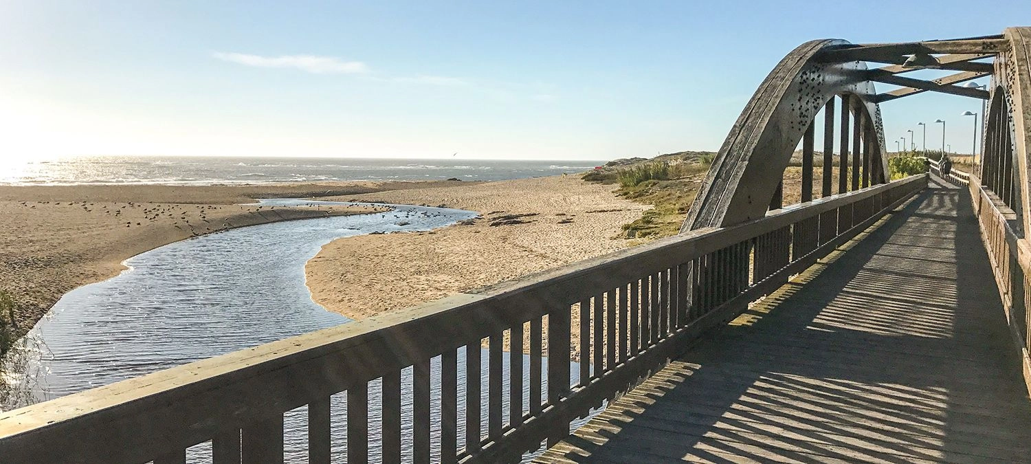 Fietsroute langs de Atlantische kust in Portugal met brug, strand en oceaan tijdens fietsvakantie naar Santiago de Compostela