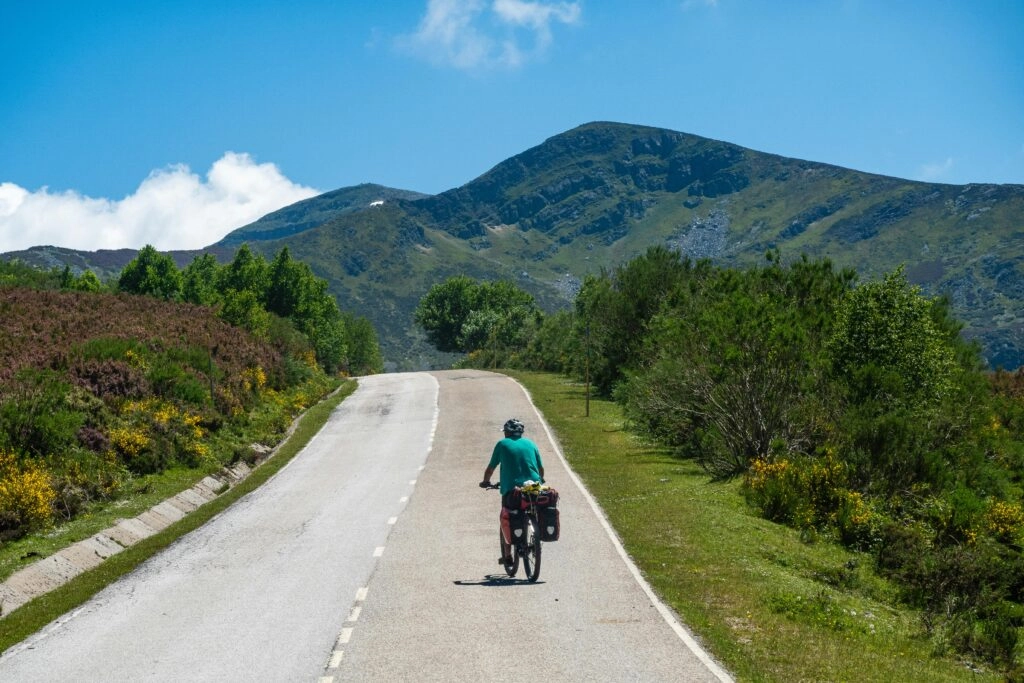 Fietser met volle fietstassen op de Camino Portugués, onderweg door de groene heuvels van Galicië richting Santiago de Compostela